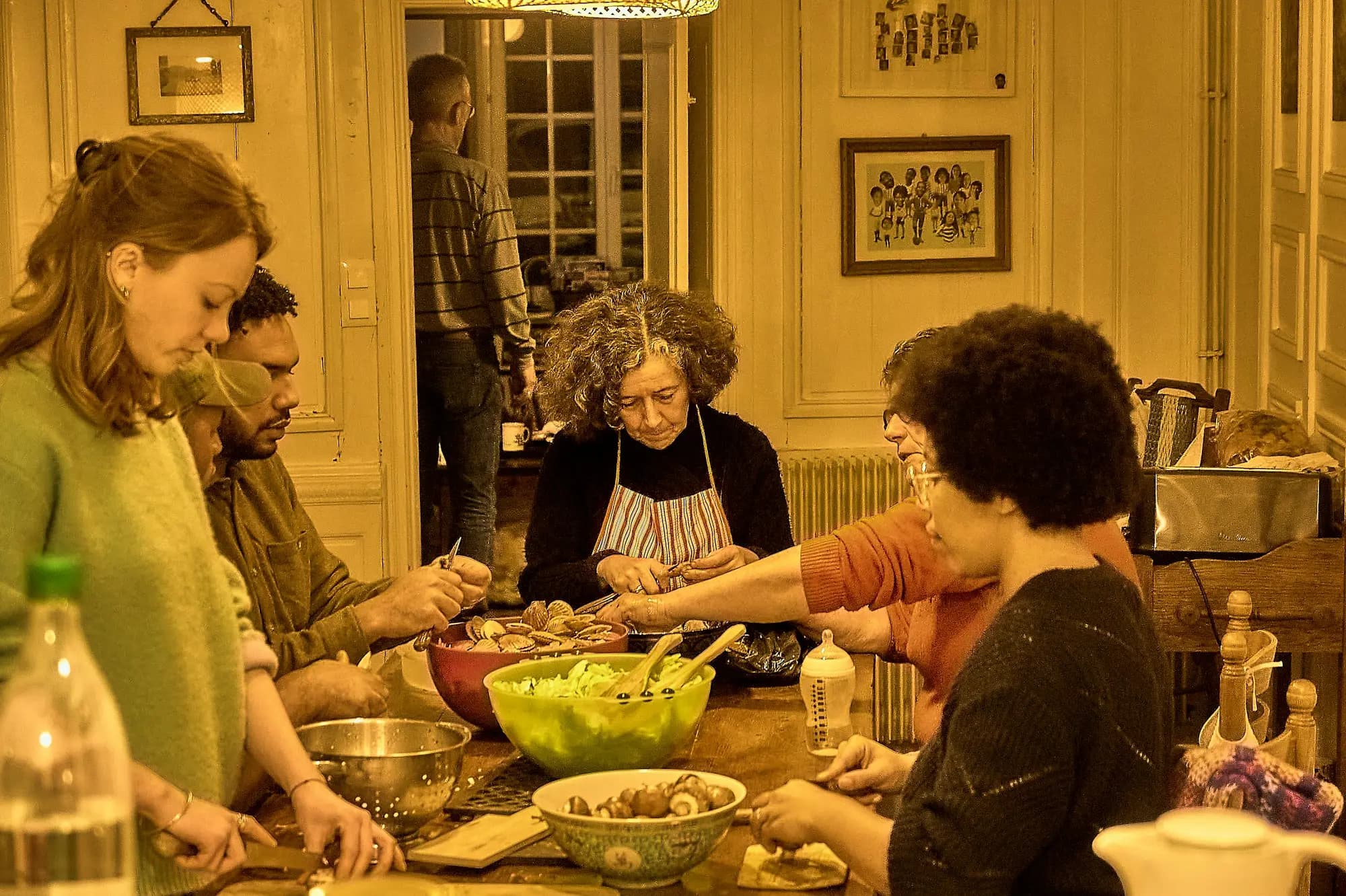 A group of people chop vegetables and prepare food together around a kitchen table