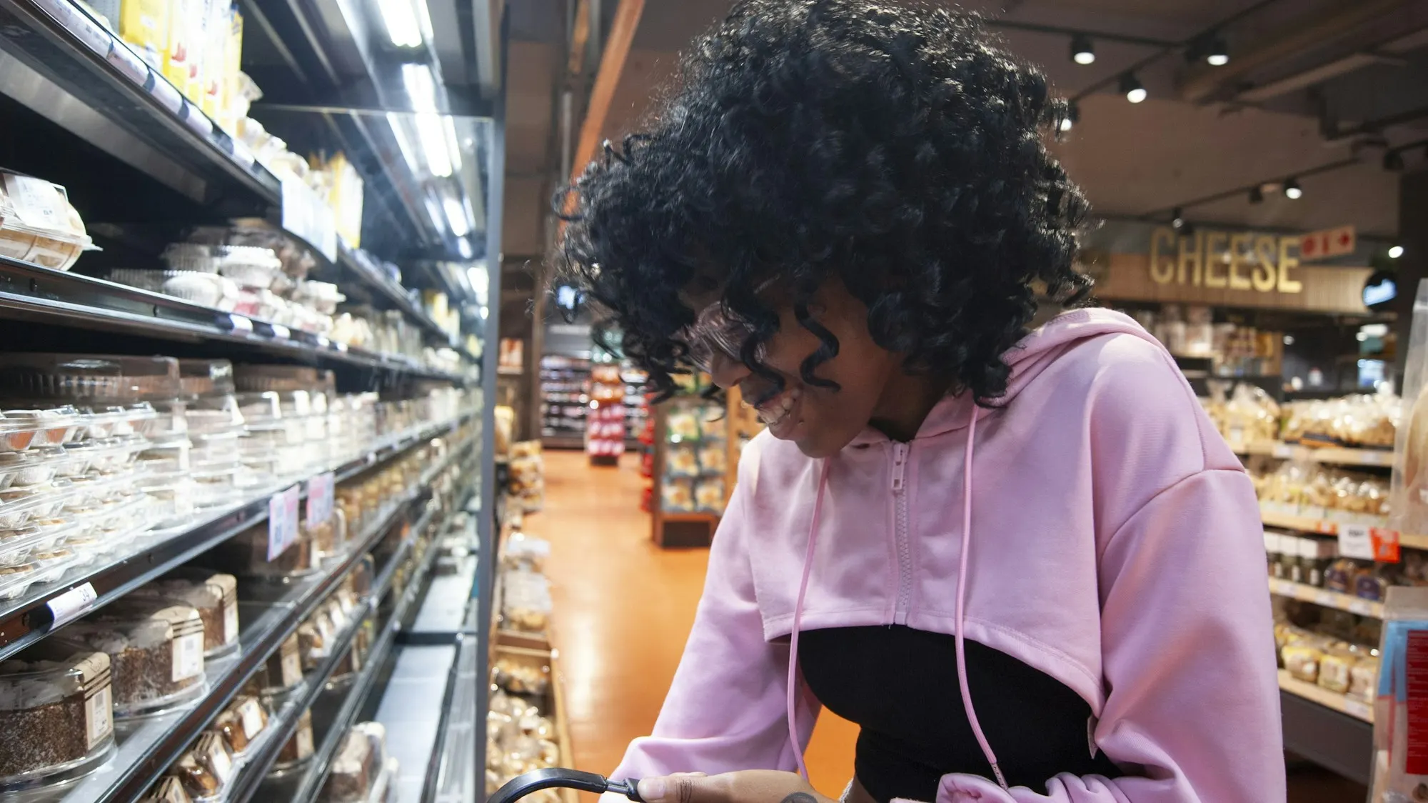 A young woman checks her phone while shopping in a grocery store aisle